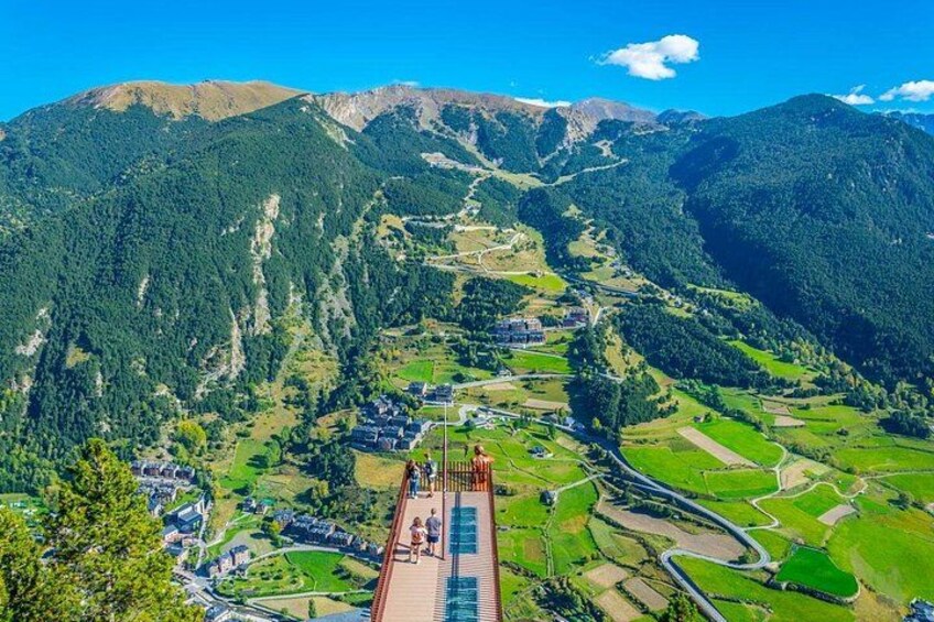 A mountainous landscape with a bridge, green fields, and a village. 3