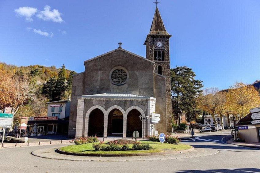 A church with a clock tower, a round window, and a small garden in front. 4