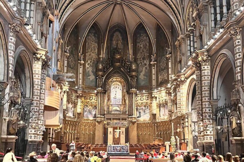 Un vaste intérieur de cathédrale, avec de hauts plafonds en voûte d’ogives, des décorations somptueuses et un autel central. 2