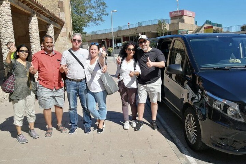 A group of people posing for a photo in front of a building with stone columns and a parked car. 3