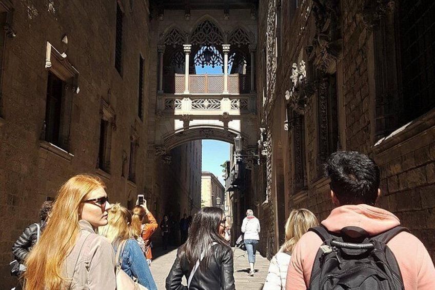 Una calle estrecha con turistas caminando hacia un arco gótico. 2