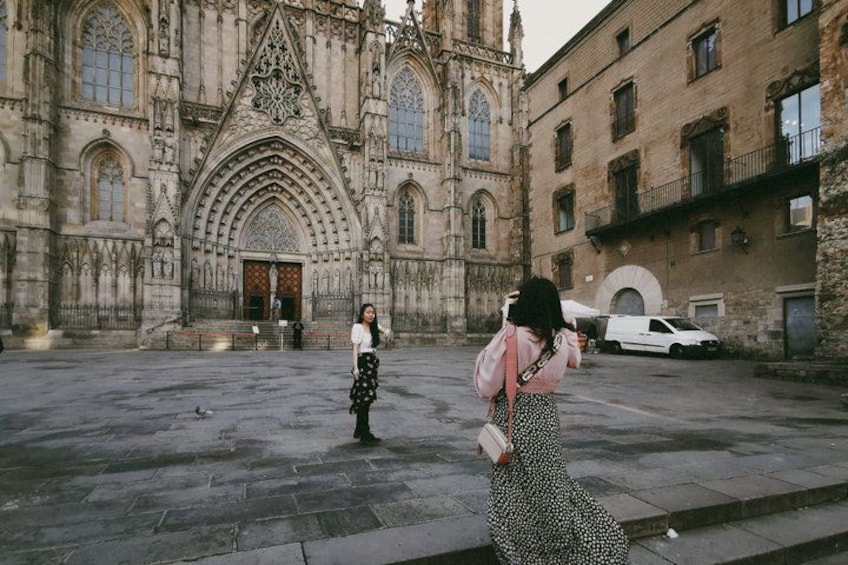 A historic cathedral with intricate architecture, a paved square, and a white car parked nearby. 1