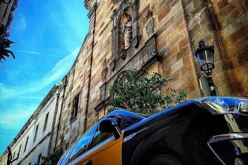 A building with classical architecture, parked cars, and a clear blue sky. 3