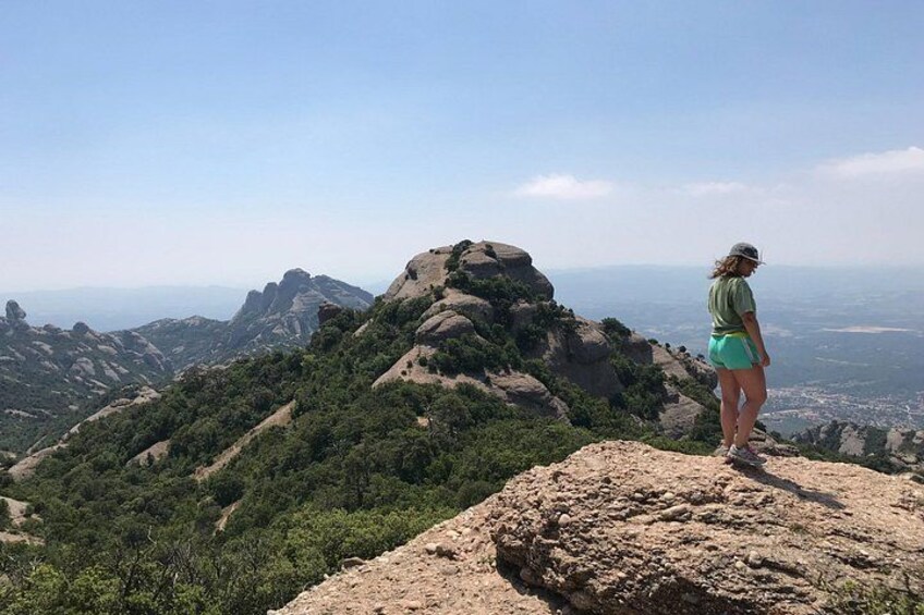 A person standing on a rocky outcrop overlooking a mountainous landscape. 1