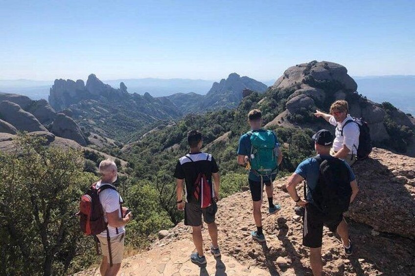 A group of hikers on a mountain trail with rocky terrain and a panoramic view of the landscape. 5