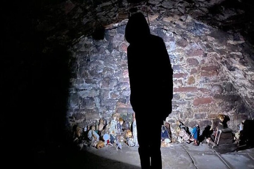 En person står i en svagt upplyst stontunnel med en grov och ojämn vägg. 2