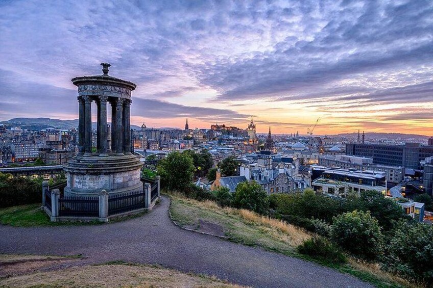 A cityscape with a prominent monument in the foreground and a sunset in the background. 4