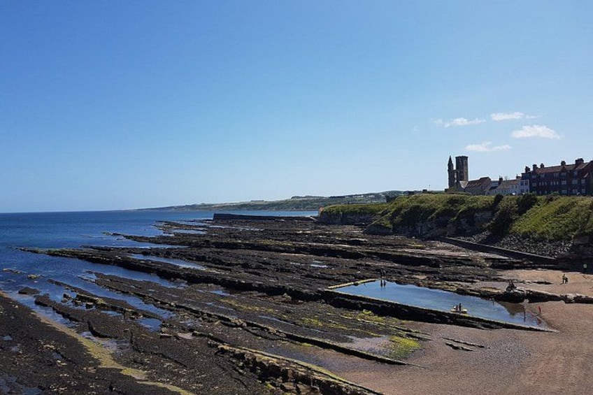 A rocky beach with a historic building in the background. 3
