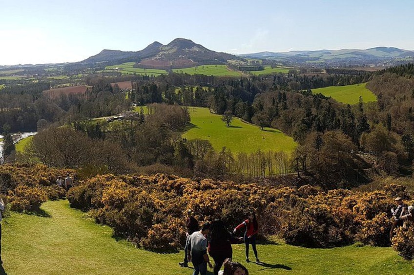 A hiker on a trail, lush green fields, and rolling hills in the background. 5