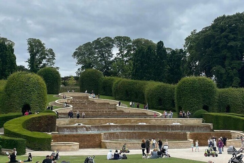 A formal garden with a central water feature, tiered steps, and neatly trimmed hedges. 5