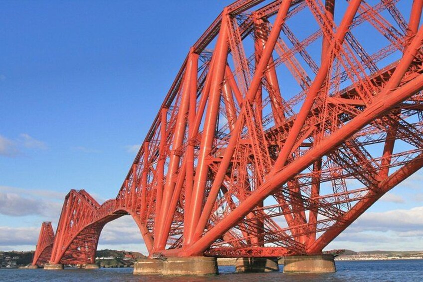 Un puente de acero rojo con múltiples arcos sobre un cuerpo de agua. 3