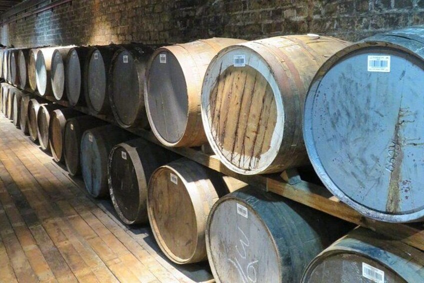 Large wooden barrels stacked in rows on wooden pallets in a warehouse. 3