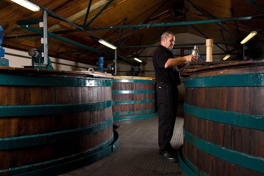 A person operating machinery in a room with large wooden barrels. 2