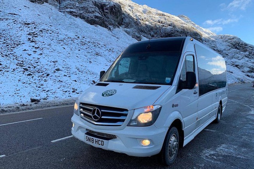 Una furgoneta blanca Mercedes-Benz Sprinter estacionada en una carretera nevada con montañas al fondo. 2