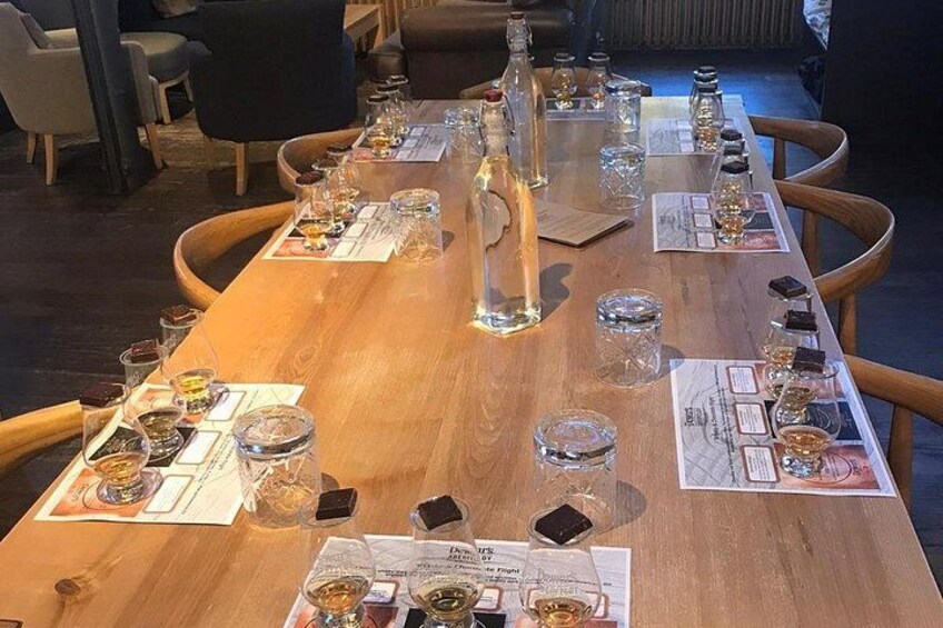 Une table en bois, sur laquelle on peut voir différentes bouteilles et différents verres, probablement pour une dégustation ou pour présenter des échantillons. 5