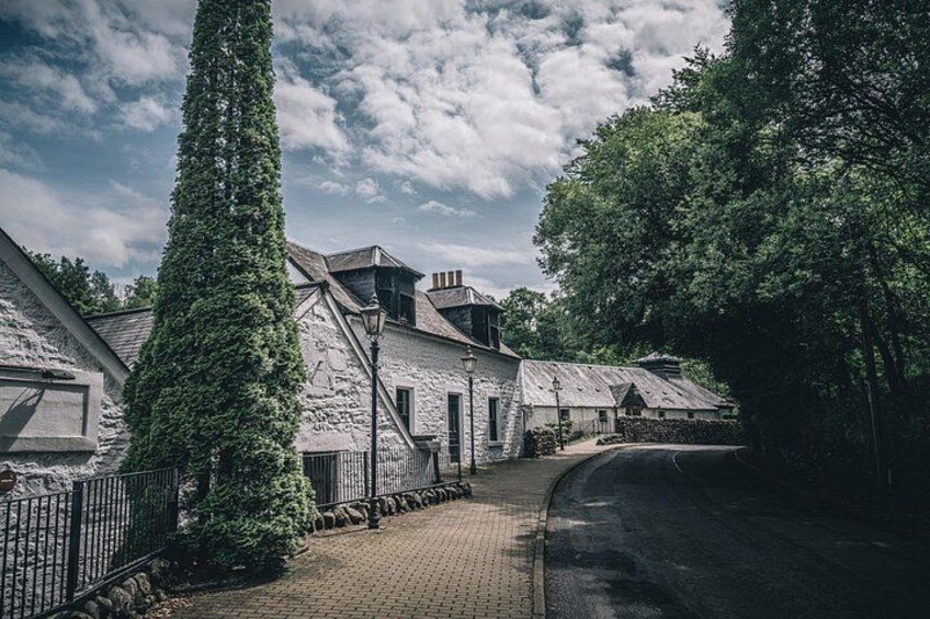 Un chemin pavé de pierres, des bâtiments en pierre et un grand arbre. 2