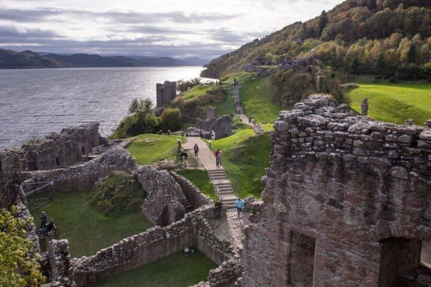 A historical site with ruins, a pathway, and a lake. 2