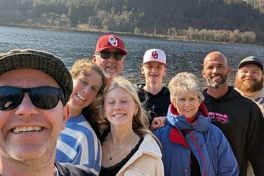A group of people on a boat with a lake and forested shoreline in the background. 3
