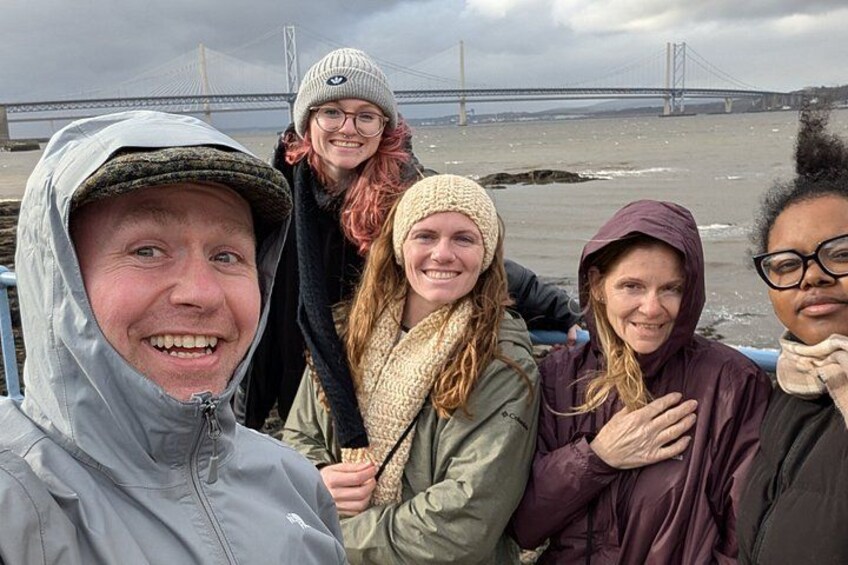 A group of people on a boat with a bridge in the background. 2