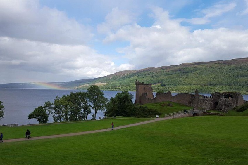 A castle ruin by a lake with a rainbow in the distance. 3