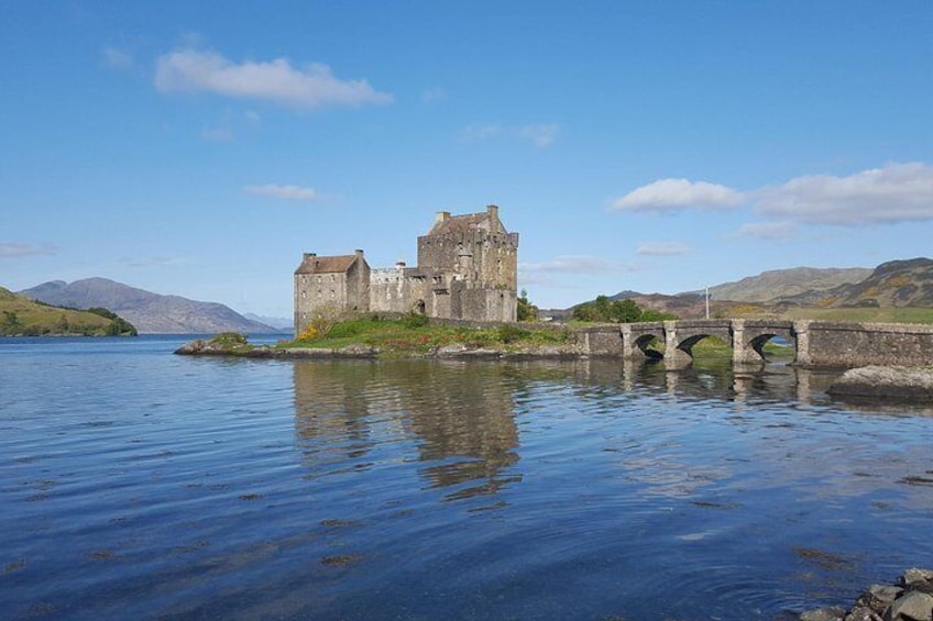 A historic castle by a calm lake with a stone bridge. 4