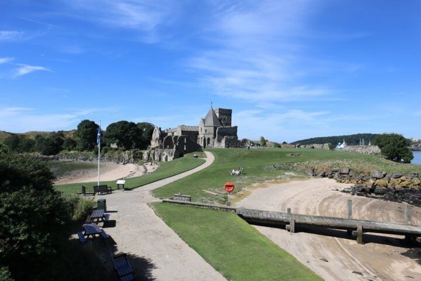 A historic building with a grassy area, a dirt path, and a wooden bridge. 2