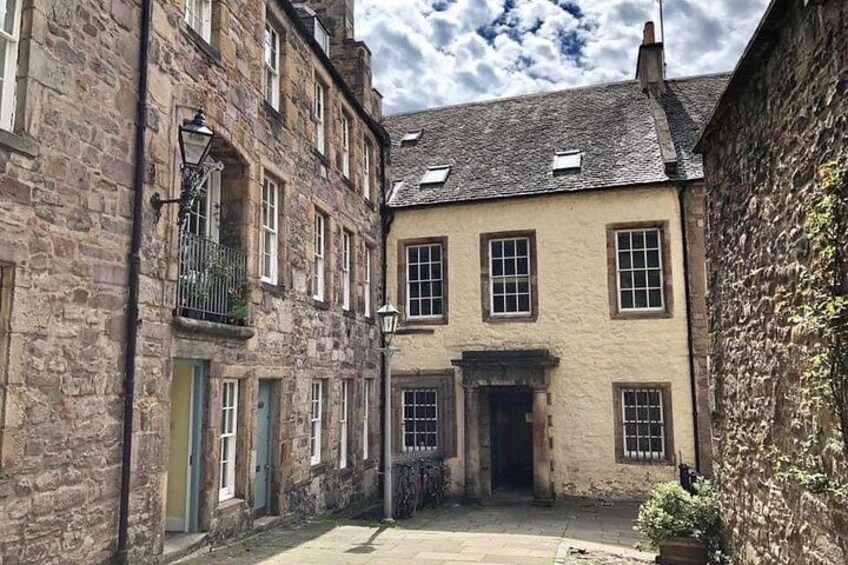 A narrow street with stone buildings, a small gate, and a clear sky. 3