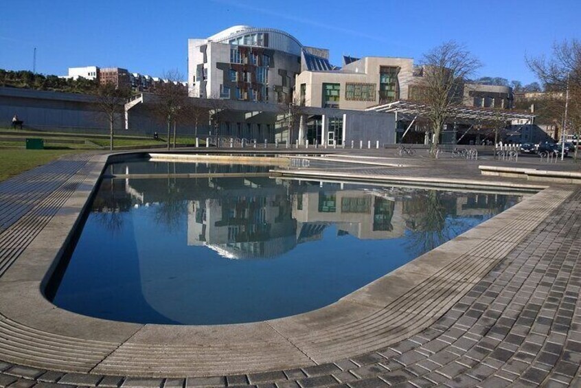 A swimming pool with a curved edge, surrounded by a brick walkway, and a modern building in the background. 3