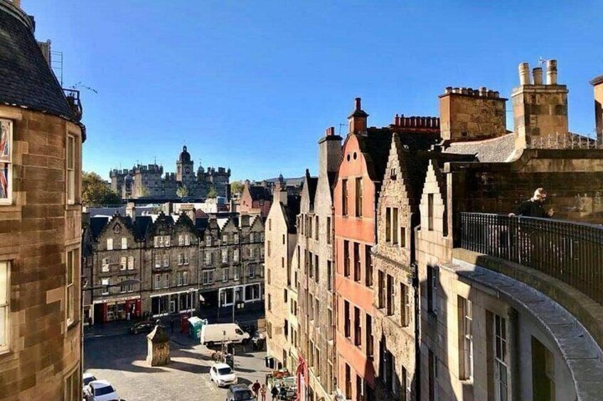 A historic town with traditional architecture, a clear blue sky, and a distant castle. 5
