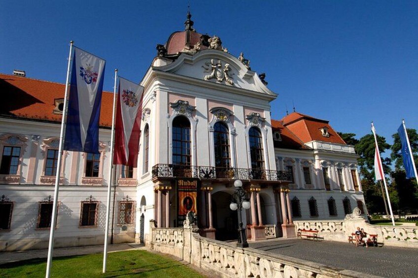 A historic building with classical architecture, flags, and a statue. 1