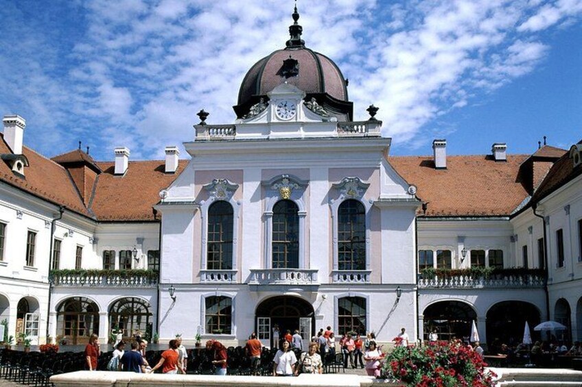 A historic building with a dome, arched windows, and a courtyard with people. 2