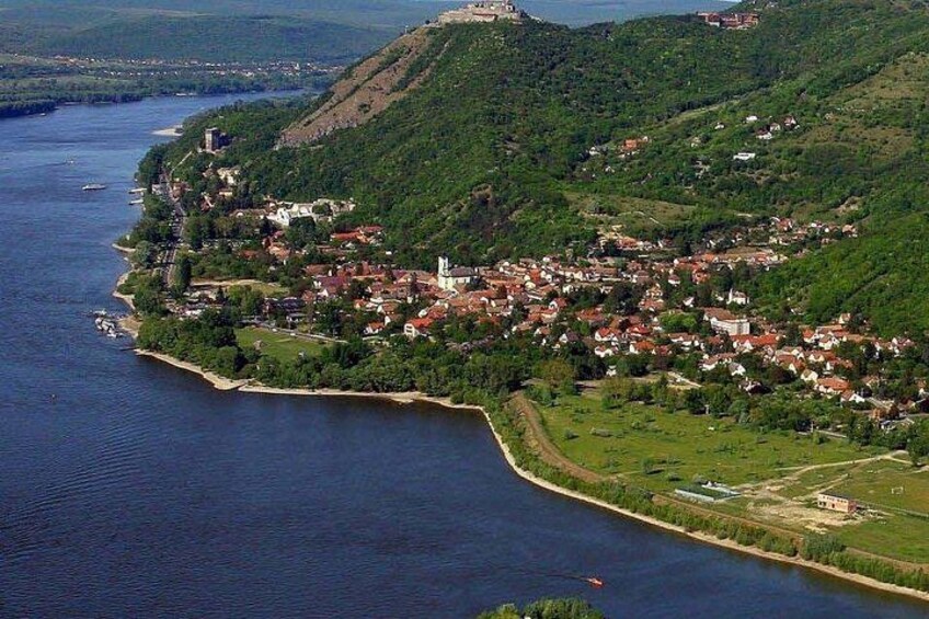 Une ville située au bord d’une rivière, avec un château perché sur une colline, le tout entouré de verdure. 2