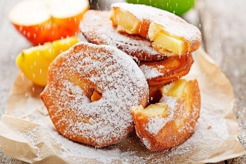 A stack of powdered donuts with apple slices on top. 2