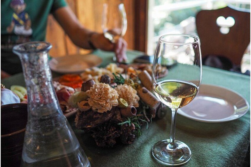 A table with a glass of white wine, a decorative vase, and a plate of food. 3