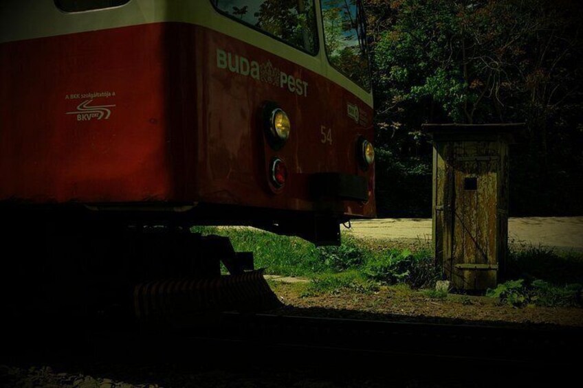 Een rode en witte trein met nummer 54, geparkeerd nabij een houten constructie. 3