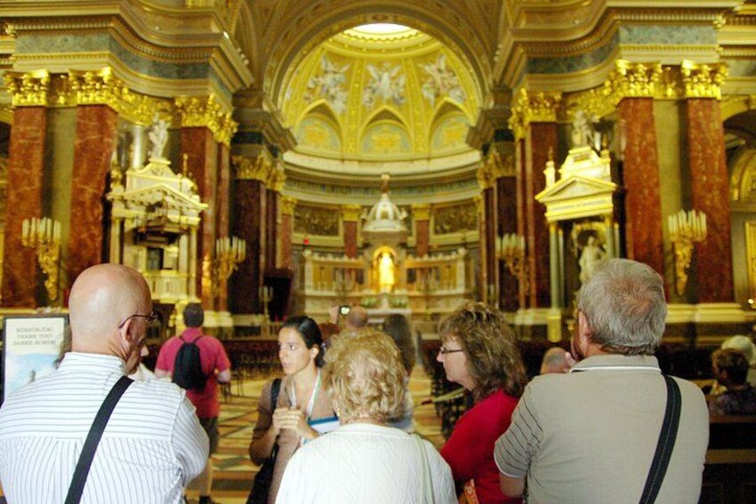 Un intérieur richement décoré, agrémenté de touches dorées et dominé par un autel central. Des personnes se sont rassemblées autour et observent les lieux. 4
