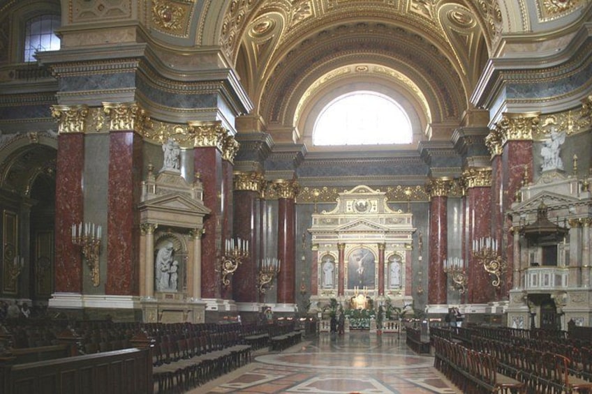 L’intérieur d’une église richement décorée, avec un plafond voûté élevé, des colonnes de marbre et un autel central. 3