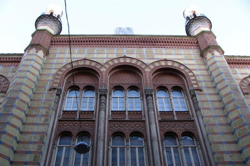 A building with arched windows, brickwork, and two domed towers. 3