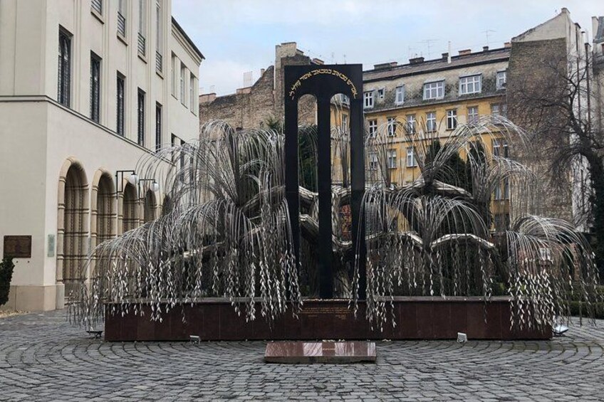 A fountain with water jets in a cobblestone plaza, surrounded by buildings. 4