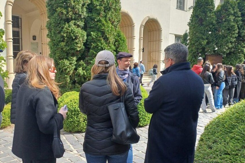 A group of people standing in a courtyard with a building in the background. 2