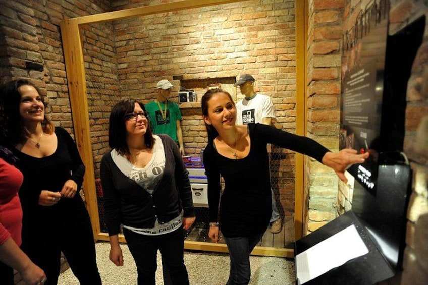 A group of people in a room with brick walls and a wooden door. 3