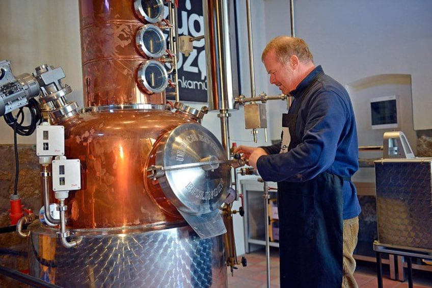 A person working with a large copper distillation apparatus in a laboratory setting. 2