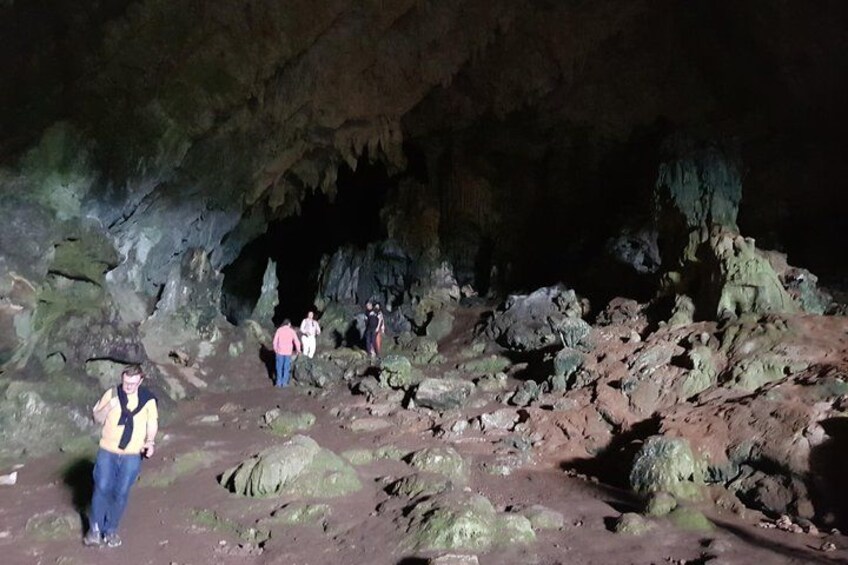 A cave with rocky formations and people exploring. 2