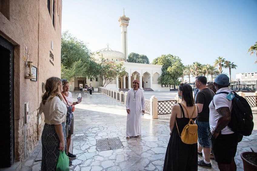 A group of people standing on a paved walkway with a mosque and minaret in the background. 4