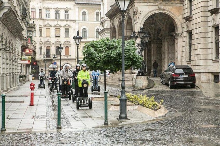 A street scene with people riding electric scooters, a red fire hydrant, and a parked car. 5