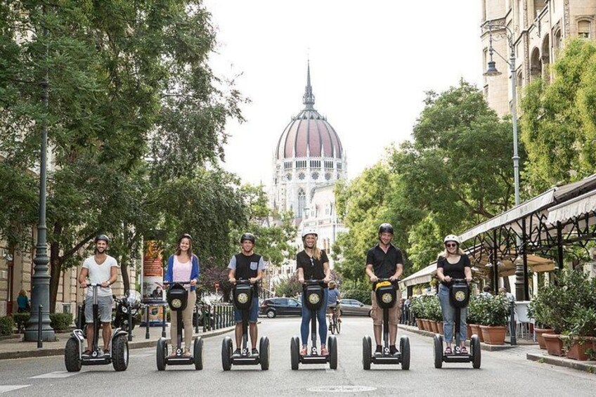 A group of people on segways on a street with a large domed building in the background. 2
