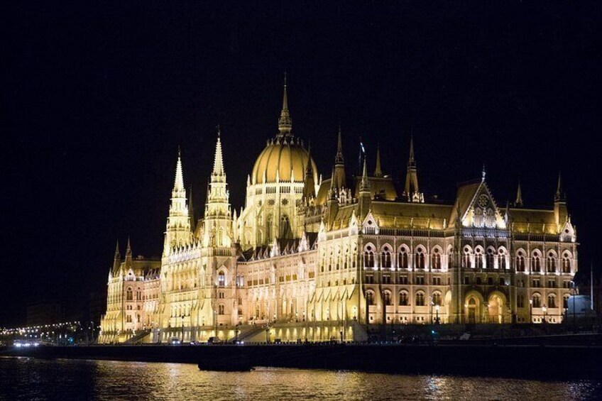 A grand, illuminated building with multiple spires and domes, reflecting on the water. 2