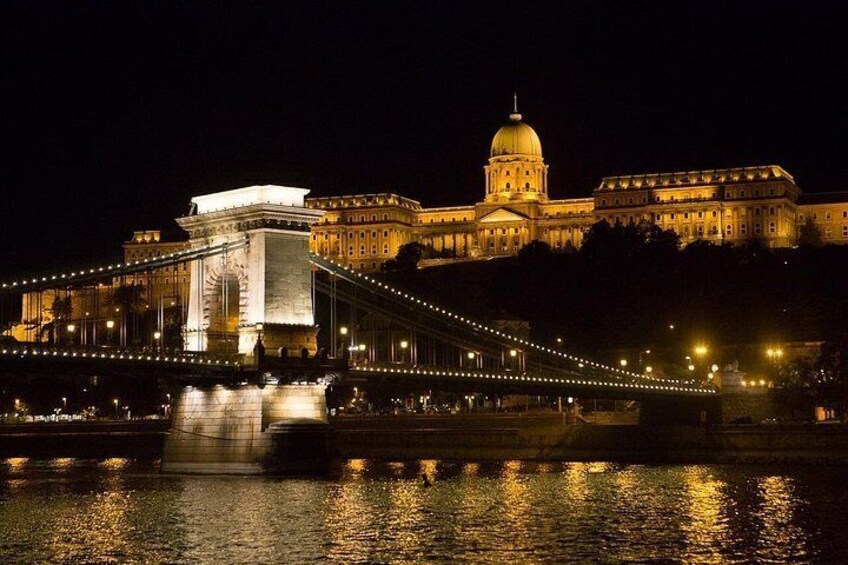 A bridge with lights, a large building with a dome, and reflections on water. 1