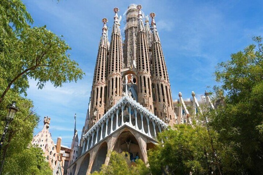 The Sagrada Familia with its intricate spires and arches, surrounded by trees. 1