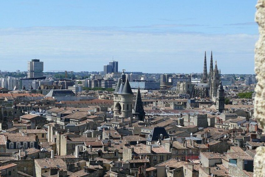 Een stadsgezicht met historische gebouwen, een opvallende kathedraal met twee torens, en moderne wolkenkrabbers op de achtergrond. 4